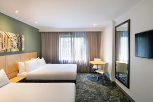 una camera d'albergo con due letti e un tavolo di Mercure Melbourne Southbank a Melbourne