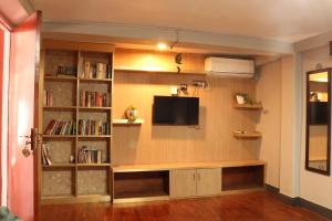 a living room with a tv and a book shelf at Apartment Elegant Kathmandu in Kathmandu