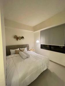 Seturanにある1BR ALTUZ Apartment by MJ Propertyの白いベッドと薄型テレビのある寝室