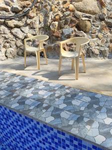 - deux chaises en plastique installées à côté de la piscine dans l'établissement Homestay Teratak D`kemangi with Private Pool, à Baling