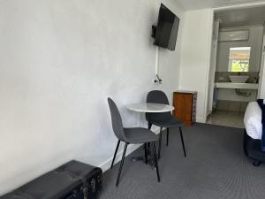 a room with a table and two chairs and a tv at Happy Wanderer Motel Bendigo CHILDREN NOT PERMITTED over 18s only in Bendigo