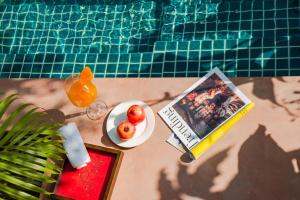 a book and a bowl of fruit next to a swimming pool at Laalee in Jaipur +9 photos