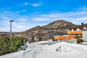 een met sneeuw bedekte straat met huizen en een berg bij Beautiful and central apartment in Oslo and Bærum in Kolsås