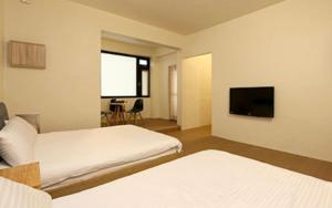 a hotel room with two beds and a flat screen tv at Bling's House in Luodong
