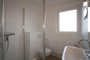 Un baño con inodoro, lavabo y ventana. en Haus Schössler, Whg 1, en Hörnum 4 fotos más