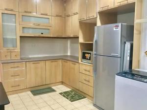 a kitchen with wooden cabinets and a stainless steel refrigerator at Prima Villa Apartment Tanah Rata Cameron Highland in Tanah Rata