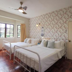 two beds in a bedroom with floral wallpaper at Prima Villa Apartment Tanah Rata Cameron Highland in Tanah Rata