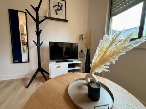 uma sala de estar com uma mesa e uma televisão em -Le Majorelle- Studio Parking Balcon Centre Wifi em Quimper