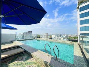 a swimming pool on top of a building with an umbrella at Palazzo Luxury Hotel in Da Nang
