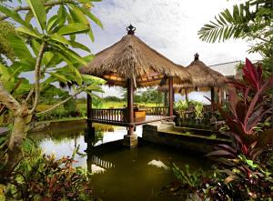 a gazebo in the middle of a pond at Lumbung Asri Cottage in Mambat