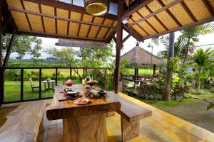 a wooden table in a room with a view of a garden at Lumbung Asri Cottage in Mambat