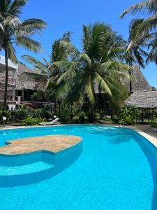 瓦塔穆Watamu Ascot Resort的背景为棕榈树的游泳池