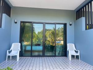 two white chairs sitting on a patio with a view of a pool at Dusit Long Beach in Ko Lanta