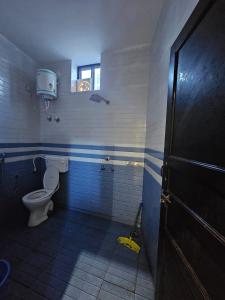 a bathroom with a toilet and a window and a mop at Gopal Hotel and Palace in Jhunjhunūn