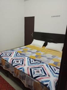 a bed with a colorful quilt on top of it at Hotel Mallard Rainbow in Bharatpur