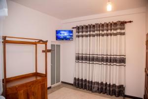 a room with a curtain and a television on a wall at Eden Sea View in Talpe