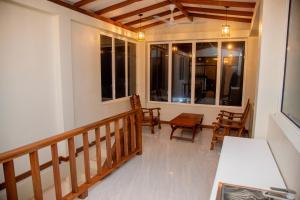 a porch with chairs and a table and windows at Eden Sea View in Talpe