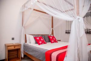 ein Schlafzimmer mit einem Himmelbett mit roten und weißen Kissen in der Unterkunft Eden Sea View in Talpe