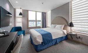 Habitación de hotel con cama grande y escritorio. en Golden Tulip Essential Namgang, en Jinju