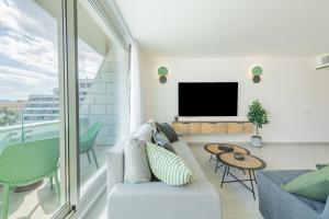 a living room with a couch and a tv at Seaside Haven-City Center Amazing Pool and Sea view in Eilat