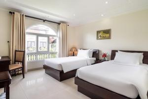 a bedroom with two beds and a desk and a window at Bonita Boutique Hotel in Ho Chi Minh City