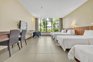 ein Hotelzimmer mit 3 Betten und einem Schreibtisch in der Unterkunft Siloso Beach Resort - Sentosa in Singapur