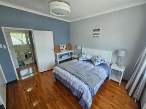 a bedroom with a bed with blue walls and wooden floors at Secure Private Flatlet in Newton Park in Port Elizabeth