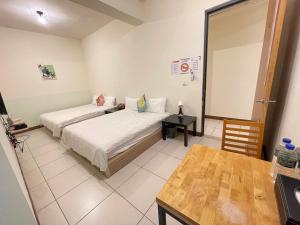 a bedroom with two beds and a table in it at 二街窩窩電梯民宿花蓮車站東出口Second street Nest Hostal in Hualien City