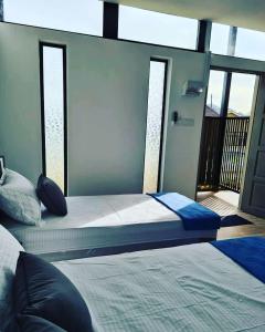 a bedroom with two beds and a balcony with windows at Laman Gadang in Johol