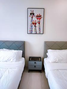 a room with two beds and a table between them at The Foreigner Staycation at Riverine Diamond Kuching in Kuching