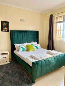 a bed with a green headboard in a bedroom at Luxe suite (1bedroom) in Nambale