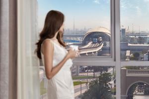 a woman in a white dress looking out of a window at Flora Al Barsha Hotel At The Mall in Dubai