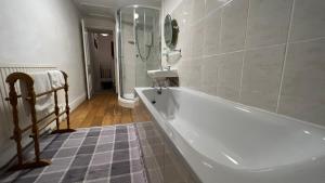 a bathroom with a tub and a sink and a mirror at Llanw Malltraeth - Malltraeth Tides in Llangadwaladr