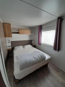 a bedroom with a large white bed with a window at Large and comfortable mobile home Clp17 2Ch Siblu Les Charmettes in Les Mathes