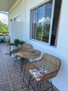 a patio with three chairs and a table and a window at Coconut Inn Moalboal in Moalboal