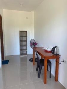 a room with a wooden table and a fan at Coconut Inn Moalboal in Moalboal