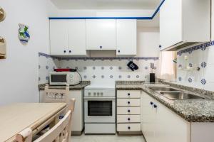 a small kitchen with white cabinets and a sink at Apartamento los Hermanos in Es Pujols