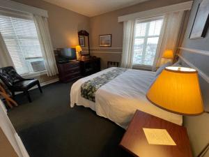 Habitación de hotel con cama y mesa con lámpara en Kalispell Grand Hotel, en Kalispell