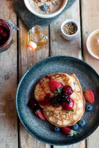 a plate of pancakes with strawberries and blueberries on a wooden table at Lofoten Cottages in Nussfjord