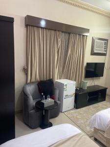 a room with a chair and a television and a bed at Arabian Palm Hotel in Rabigh
