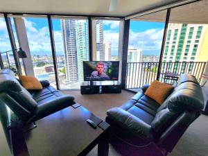 a living room with two leather couches and a flat screen tv at Great location and amazing views in Brisbane