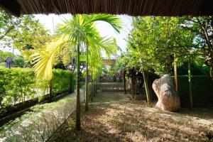 uma palmeira num jardim ao lado de uma cerca em Citrus Village Villa Hoi An em Hoi An