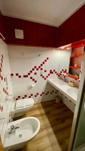 e bagno con lavabo, servizi igienici e piastrelle rosse e bianche. di Lys Apartment a Gressoney-la-Trinité