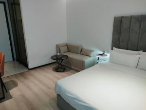 a bedroom with a bed and a chair and a couch at Shanghai Ange Hotel - Next to Longyang Road Subway Station, Near New Internatonal Expo Center in Shanghai