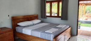 sypialnia z łóżkiem z drewnianą ramą i oknem w obiekcie Adventure Turtle Homestay Meru Betiri w mieście Sarungan