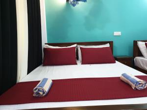 a bedroom with a bed with red pillows and two towels at Raymond Place -REDSTAR in Weligama