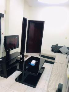 a living room with a television and a couch at العلمين للشقق المخدومة in Al Jubail
