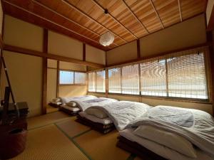 two beds in a room with two windows at 古民家の宿 鎌倉楽庵 in Kamakura