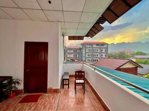 balcón con 2 sillas y vistas a un edificio en Easy go backpacker hostel, en Vang Vieng