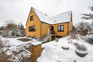 een geel huis met sneeuw op de grond bij FeWo PeDa Nord in Norderstedt